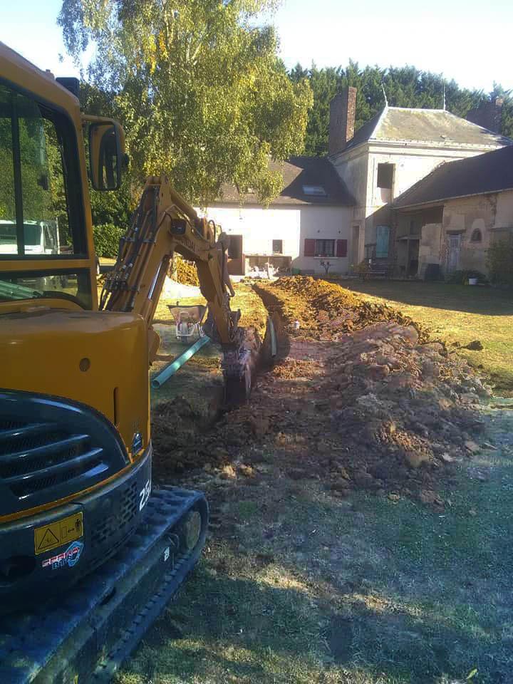 Photo d'une mini-pelle de chantier qui creuse une tranchée pour préparer l'installation d'une filière de traitement d'eaux usées.